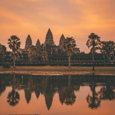 Tranquil sunrise view of Angkor Wat reflecting in calm lake waters, Siem Reap, Cambodia.