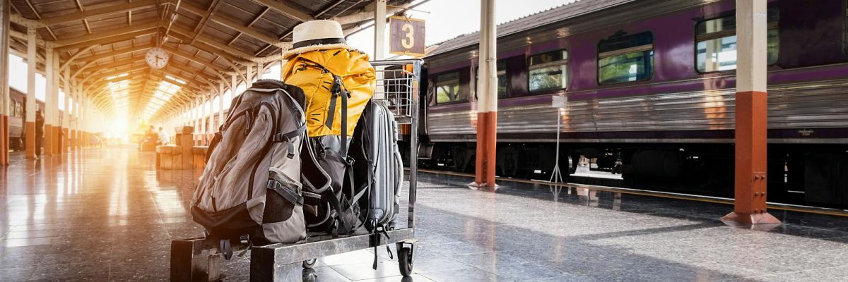 A traveler's baggage cart on an urban railway station platform at sunrise.